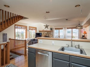 Una cocina con una escalera de madera, una chimenea de piedra y una isla grande con un fregadero.