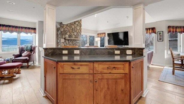 A kitchen with wooden cabinets, a stone accent wall, and a large window.