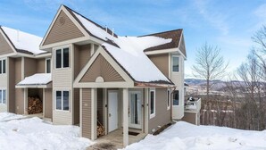 A two-story house with a snow-covered roof and a front porch.