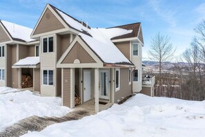 Una casa a due piani con tetto imbiancato dalla neve e un portico.