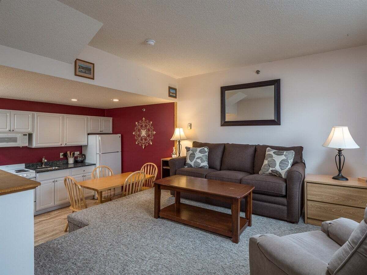 A compact living space with a kitchenette, a dining area, a sofa, and a small table.
