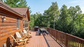 En träveranda med Adirondack-stolar, en grill och ett picknickbord.
