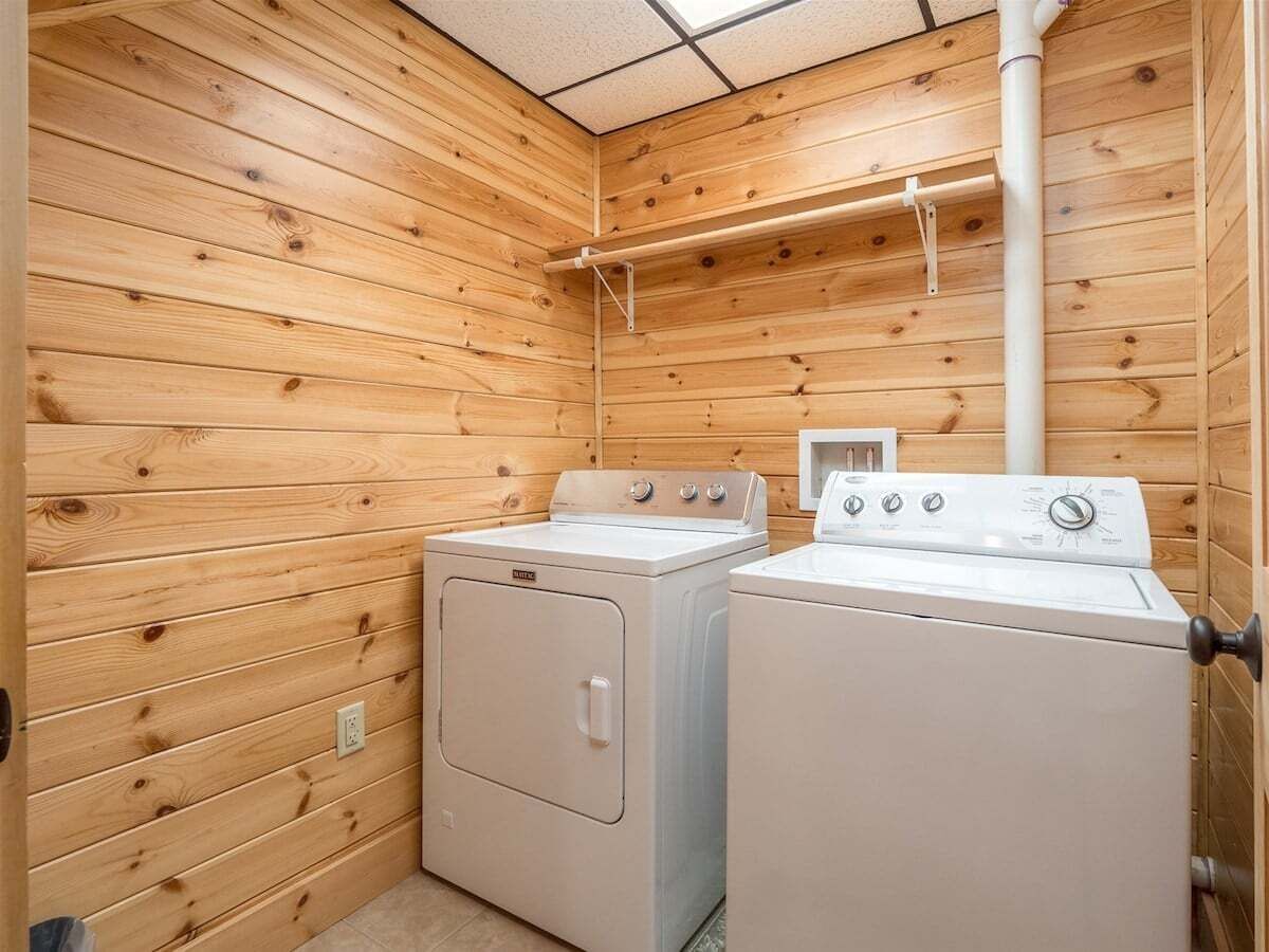Une buanderie avec des murs en bois, deux machines à laver et un sèche-linge.