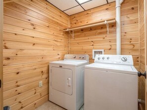 Une buanderie avec des murs en bois, deux machines à laver et un sèche-linge.