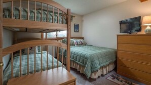 A room with bunk beds, a television, a dresser, and a window. - White Cap B-312 - Sunday River Condo (Newry)
