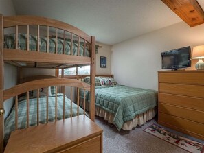 Ein Zimmer mit Etagenbetten, einem Fernseher, einem Schminktisch und einem Fenster.