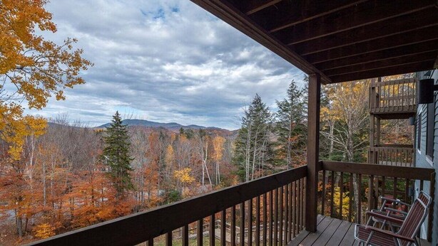 A wooden deck with a view of autumn foliage and mountains. - White Cap B-312 - Sunday River Condo (Newry)