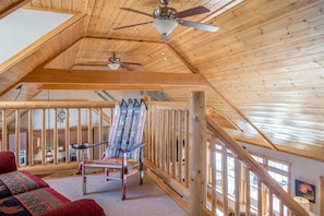 Un intérieur en bois avec un plafond haut, une chaise et un escalier.