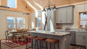 A spacious kitchen with a central island, wooden bar stools, and pendant lighting.
