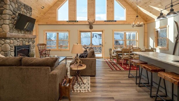 A spacious loft-style interior with a stone fireplace, a dining area, and a kitchen with a bar.