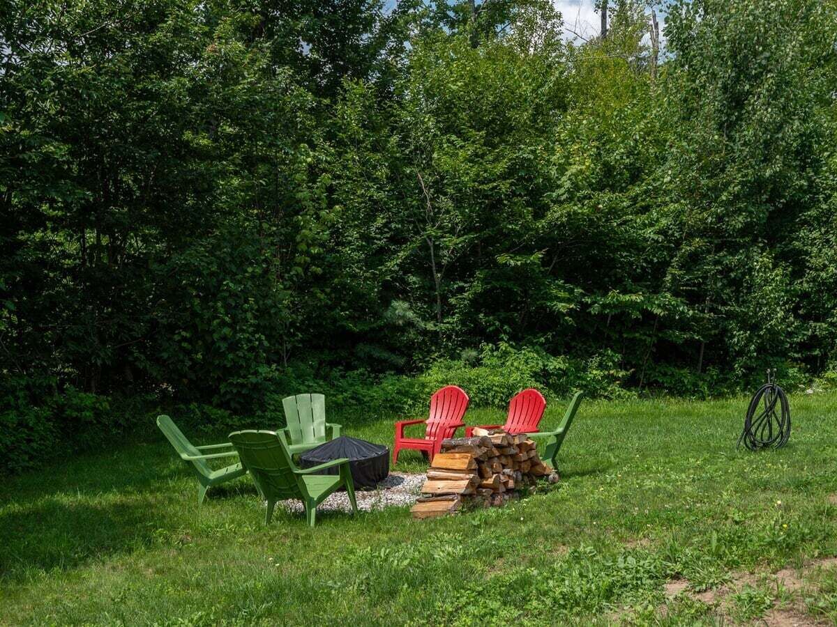 An outdoor seating area with chairs and a table, surrounded by dense greenery.