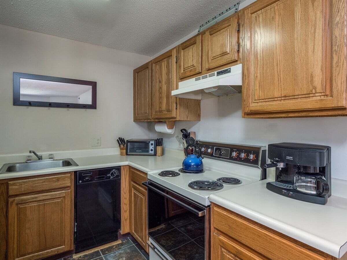 A kitchen with wooden cabinets, a stove, a dishwasher, a microwave, and a coffee maker.