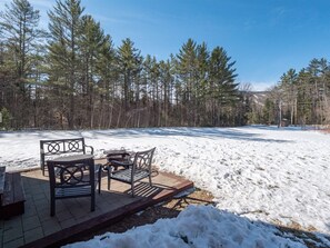 Guests can enjoy the serene view from this sheltered outdoor seating area surrounded by evergreen trees.