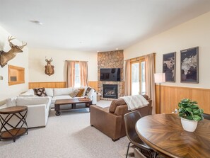 Relax in a cozy living room with a comfortable seating area, stone fireplace, and mounted TV.