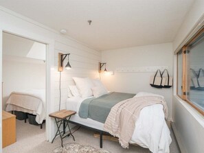 A bedroom with a bed, bedside table, lamp, and window.