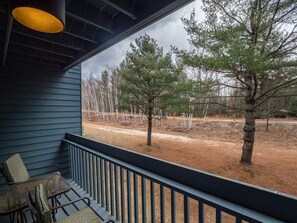 A porch with a view of trees and a dirt path.