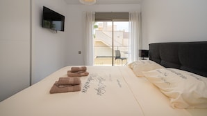 A modern hotel room with a bed, a TV, a balcony view, and a chandelier. - Apartamento Vistabella (Vistabella Golf) (Orihuela Costa)