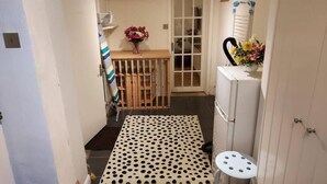 A narrow hallway with a polka dot mat, a small stool, a wooden crib, and a refrigerator. - Beautiful 3-bed House in Chatham (Chatham)