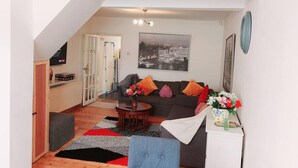 A living room with a sofa, coffee table, and a painting of a cityscape. - Beautiful 3-bed House in Chatham (Chatham)