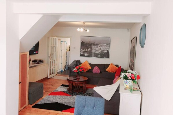A living room with a sofa, coffee table, and a painting of a cityscape.
