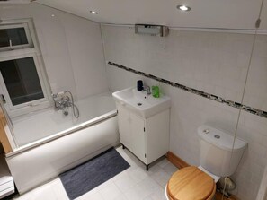 A bathroom with a bathtub, sink, toilet, and a window.