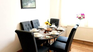 A dining table set for four with black upholstered chairs, white plates, and a vase of flowers. - Beautiful 3-bed House in Chatham (Chatham)