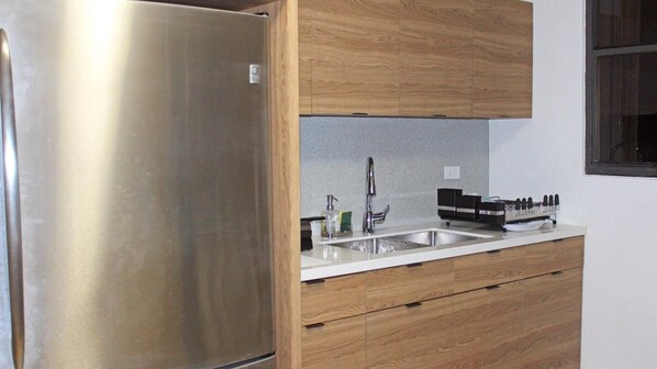 A kitchen with a stainless steel refrigerator, a double sink, wooden cabinets, and a countertop with a knife block. - bwSpacious Property to Work & Relax,1-min Walk to Beach, Ocean Views, 45 day min (San Juan)