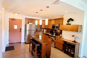 A modern kitchen with wooden cabinets, stainless steel appliances, and pendant lighting.