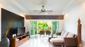 A modern living room with a flat-screen TV, a large vase, and a sofa. - Beautiful villa with swimming pool (Tambon Rawai)