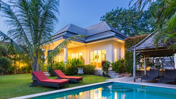 A modern house with a swimming pool, red lounge chairs, and lush greenery. - Beautiful villa with swimming pool (Tambon Rawai)