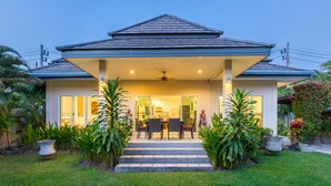 A house with a covered patio, a dining area, and a staircase leading to the entrance. - Beautiful villa with swimming pool (Tambon Rawai)