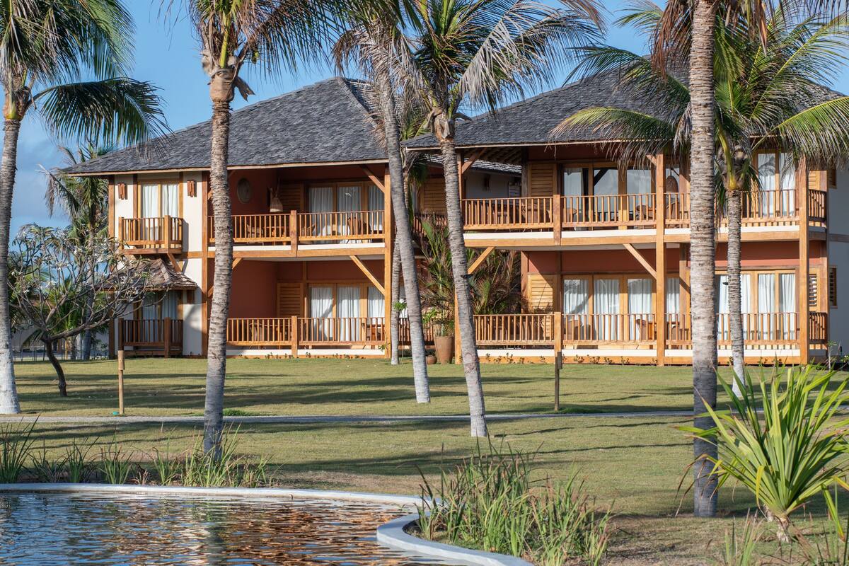 A resort with a pool, palm trees, and a two-story building with balconies.
