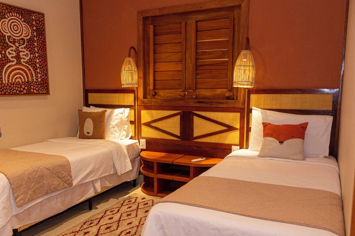 A hotel room with two beds, a wooden headboard, a small table, and wall art.