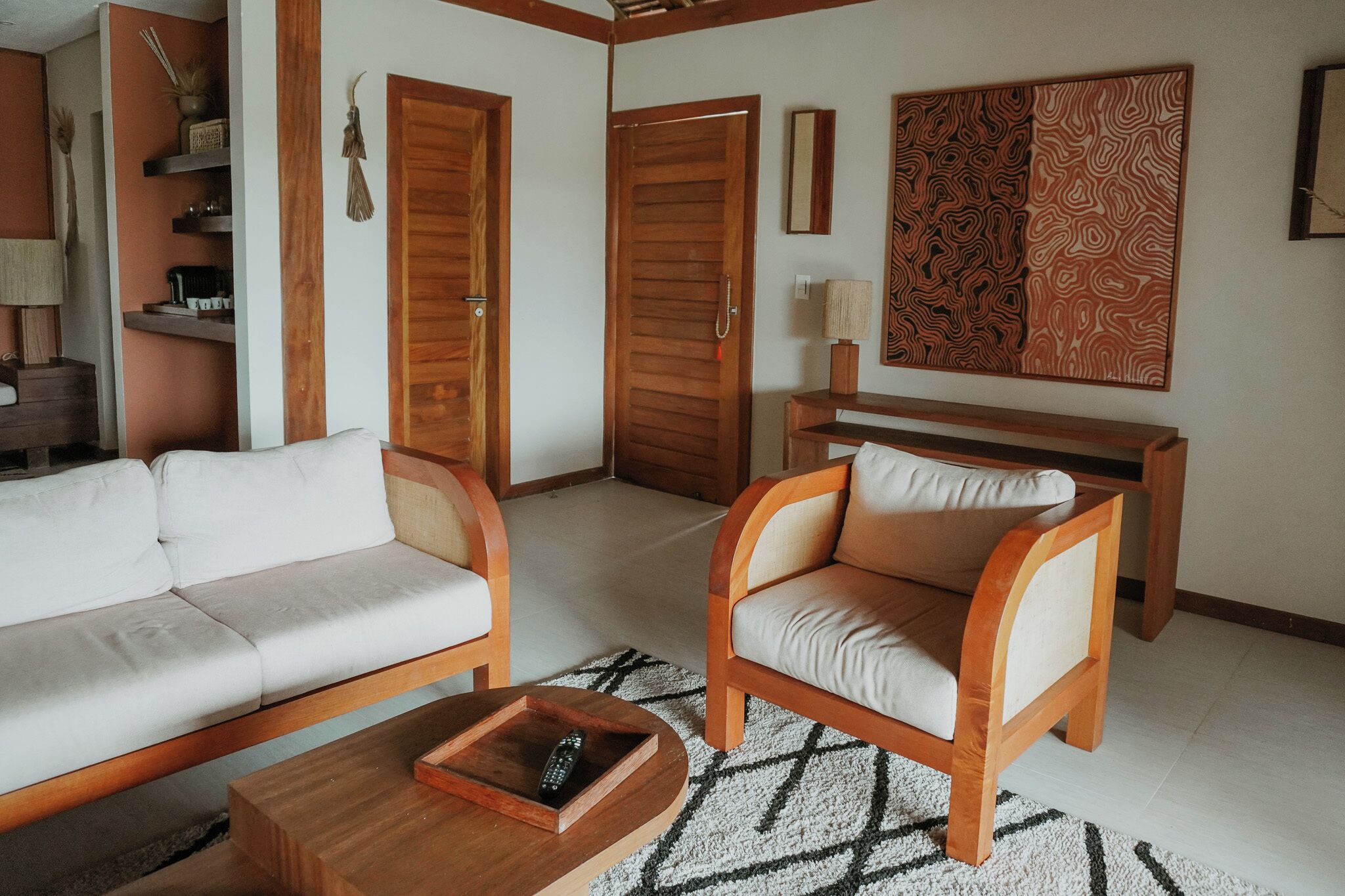 A living room with a sofa, armchair, coffee table, and a wooden side table.