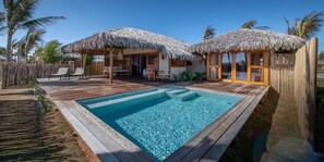 A poolside area with wooden deck, thatched-roof structures, and a clear pool. - Jaguaríndia Village (Fortim)