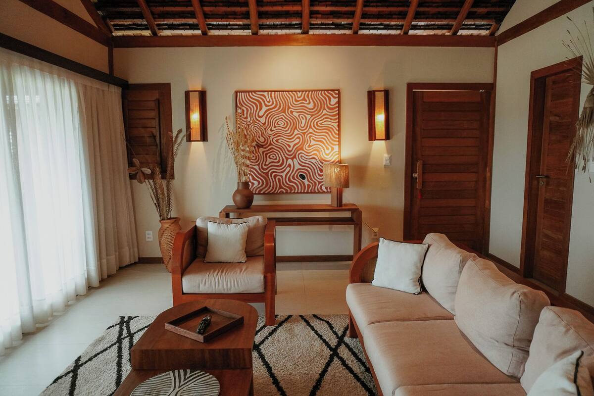 A living room with a sofa, a chair, a coffee table, a decorative vase, and a wall art piece.