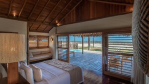 Un dormitorio con cama, mesita de noche y ventana con vista al mar.