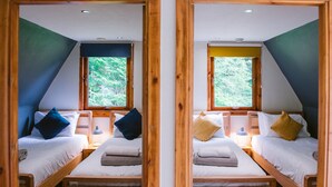 Two identical twin bedrooms with wooden frames, white bedding, and a window with a view of greenery. - Bright Star Lodge (Invergarry)
