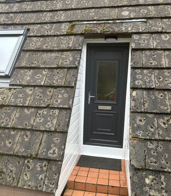 A black door with a small window above it, set in a stone wall with a white trim. - Bright Star Lodge (Invergarry)