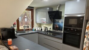 A compact kitchen with a built-in oven, a microwave, and a toaster. - Bright Star Lodge (Invergarry)
