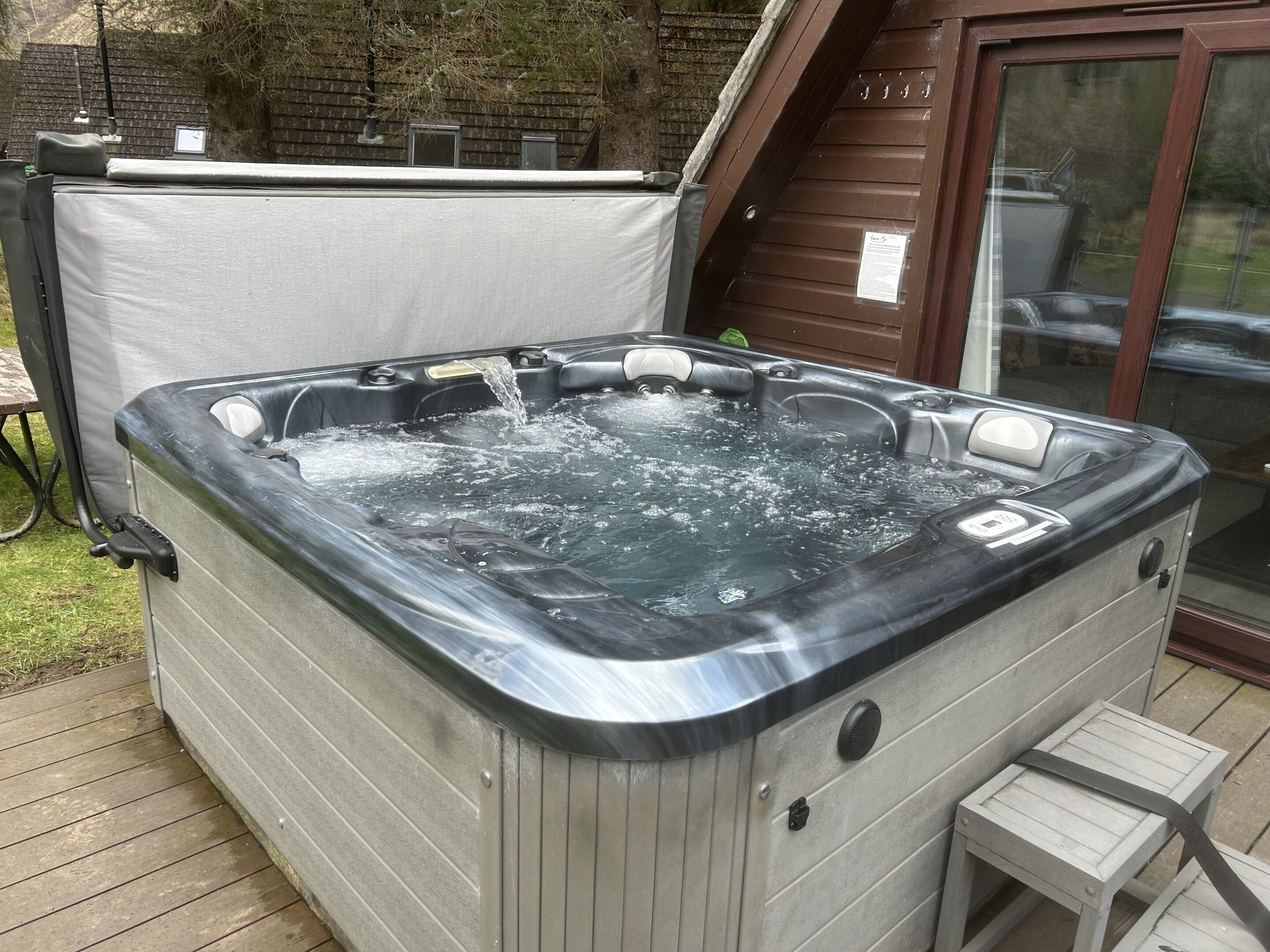 A hot tub with a wooden deck and a covered storage area.