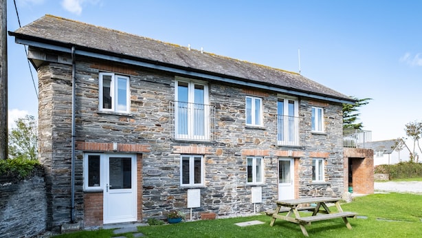 A stone building with multiple windows and a small balcony. - Stable Cottage (Port Isaac)