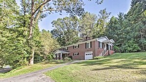 A two-story brick house with a front porch, a garage, and a well-maintained lawn.