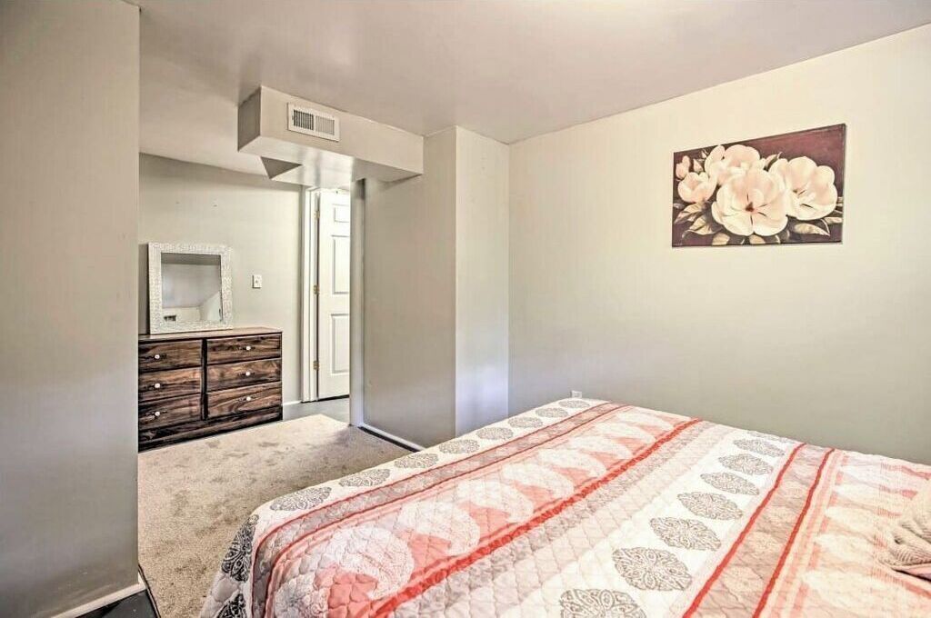 Een slaapkamer met een bed, een dressoir, een spiegel en een schilderij aan de muur.
