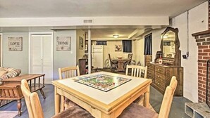 A dining area with a wooden table and chairs, a kitchen in the background, and a fireplace.
