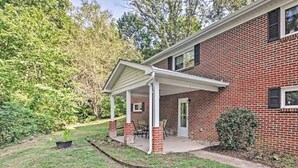 A two-story brick house with a covered porch and a small garden.