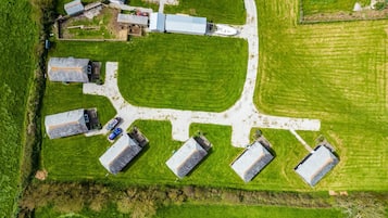 Vista aérea de una propiedad rural con varias construcciones, un amplio espacio cubierto de césped y un camino pavimentado.