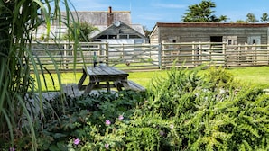 A rustic wooden barn with a laundry facility, surrounded by a wooden fence and lush greenery. - Atlantic Lodge (Port Isaac)