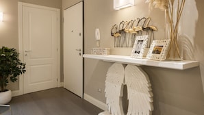 A hallway with a white door, a shelf with decorative items, and a potted plant. - Michelangelo Hideaway by Mmega (Florence)