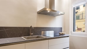 A modern kitchen with a stainless steel sink, a range hood, and a window providing a view of the outside. - Michelangelo Hideaway by Mmega (Florence)